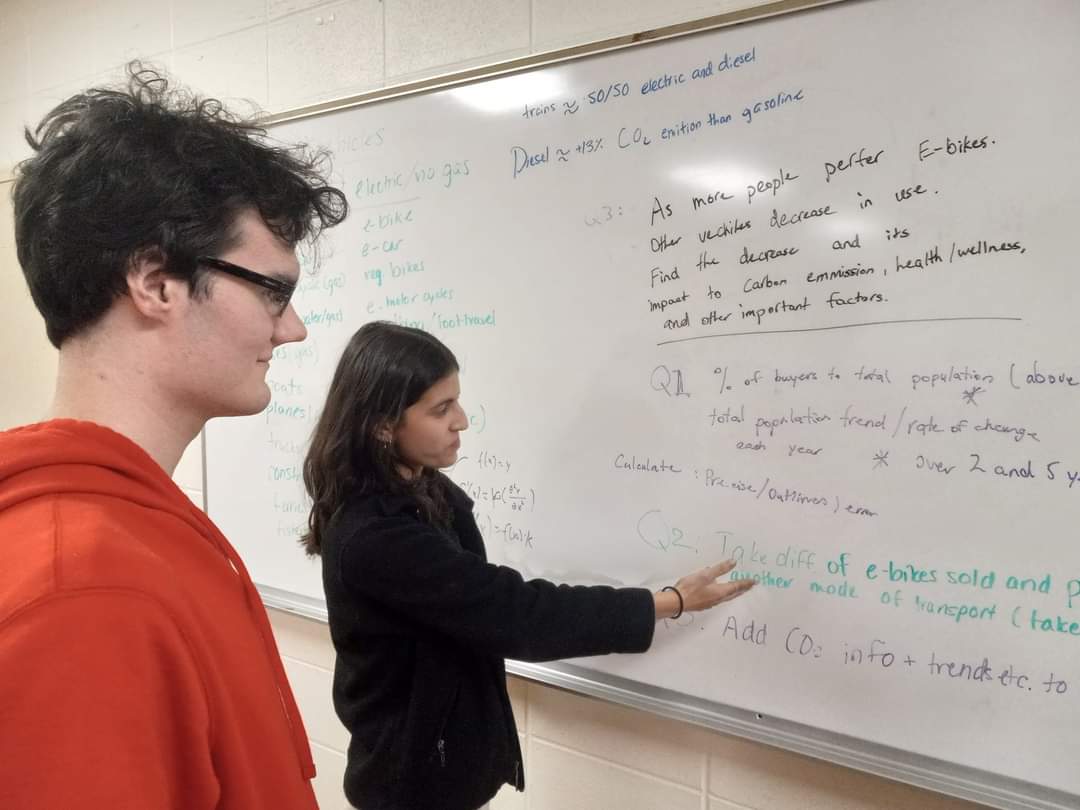 Girl showing boy something written on a whiteboard