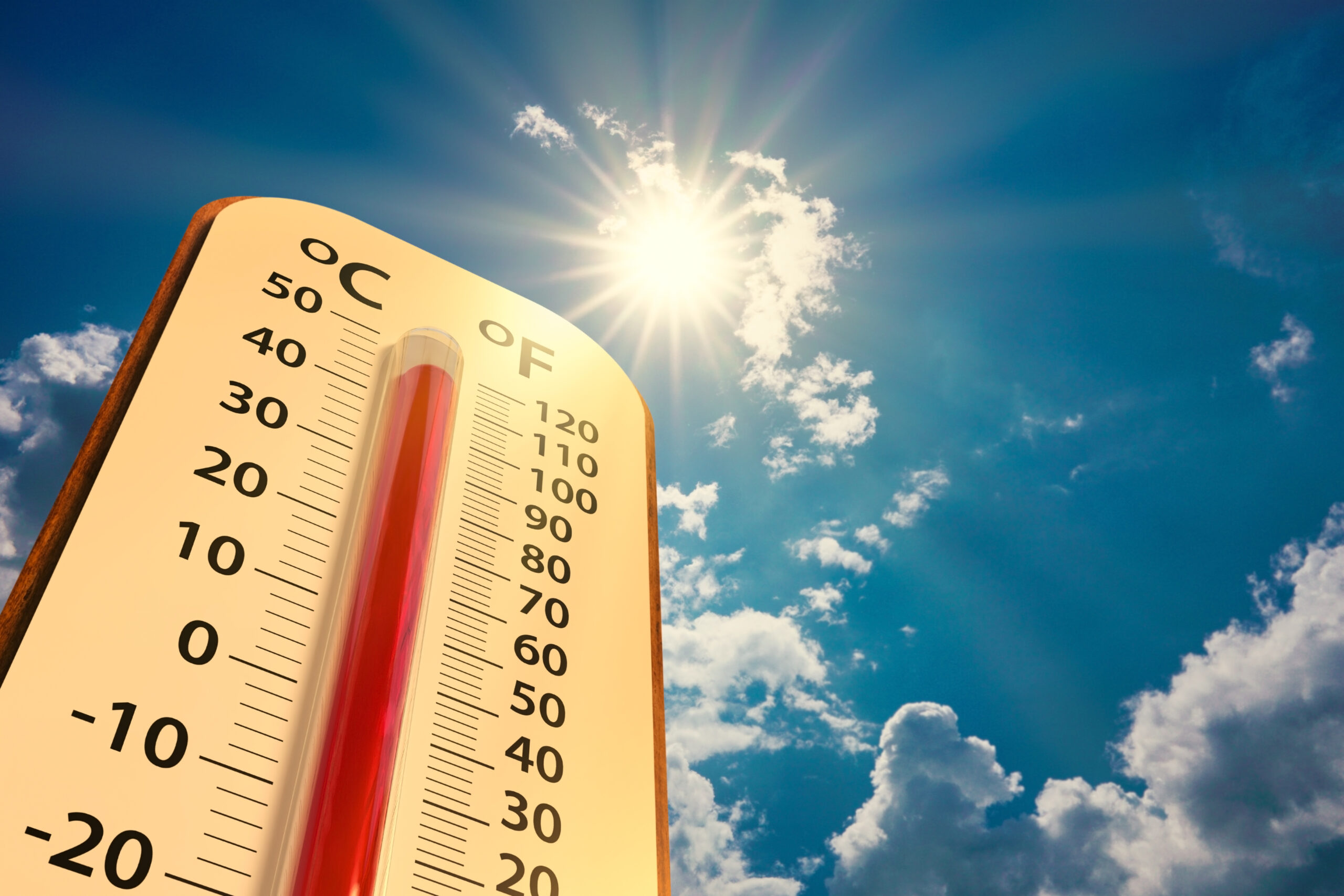 low angle view of a thermometer on blue sky with sun shining
